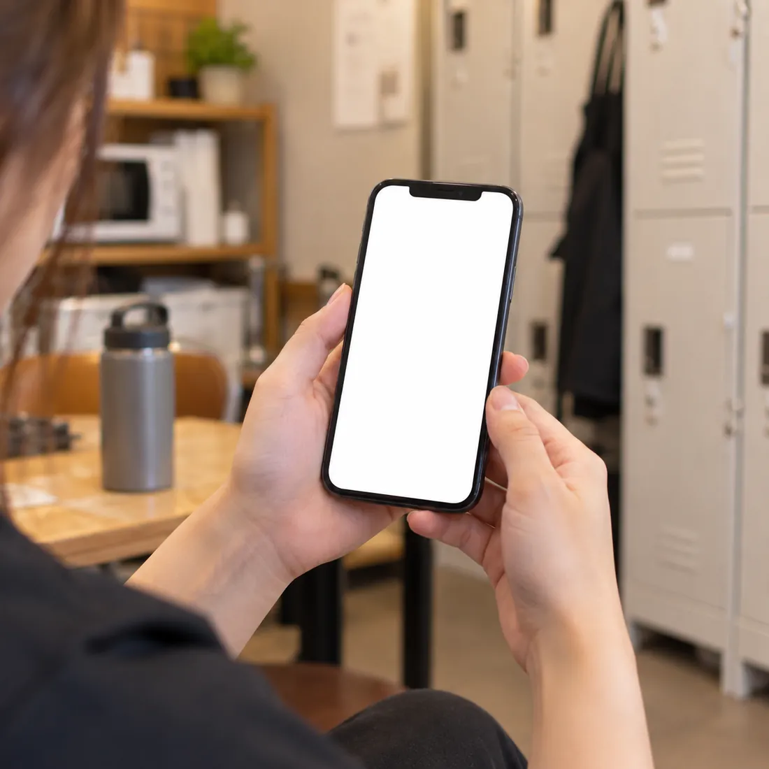 休憩室でスマートフォンを持つ手